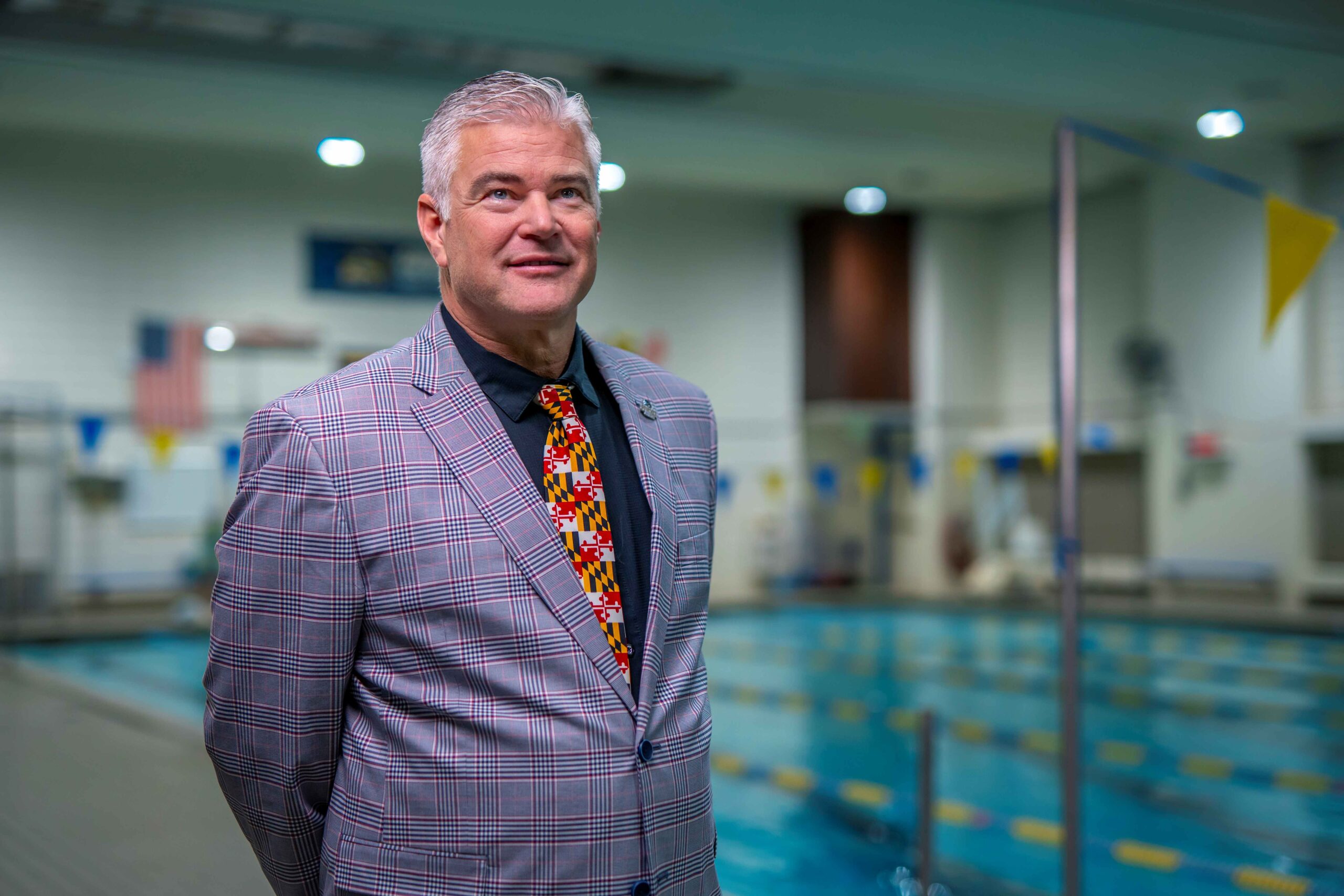 Tom Till stands in front of the Goucher pool wearing a Maryland flag tie