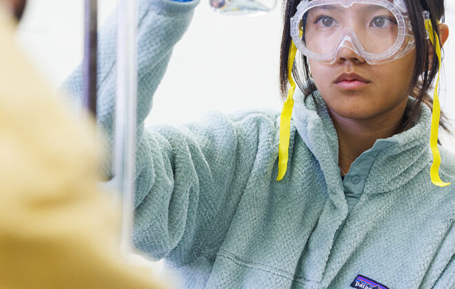 Student in science lab looking at beaker