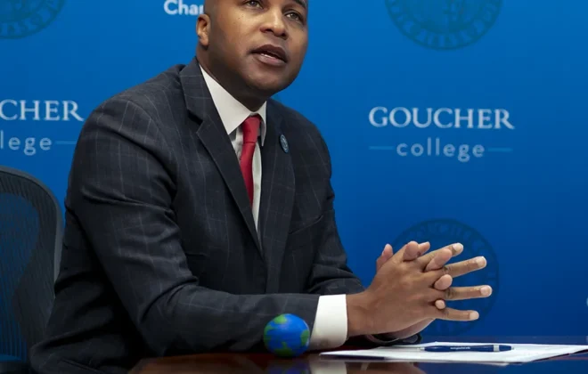Mike Marshall speaks in front of a blue Goucher background during the Goucher College and Air University, Islamabad, partnership announcement.