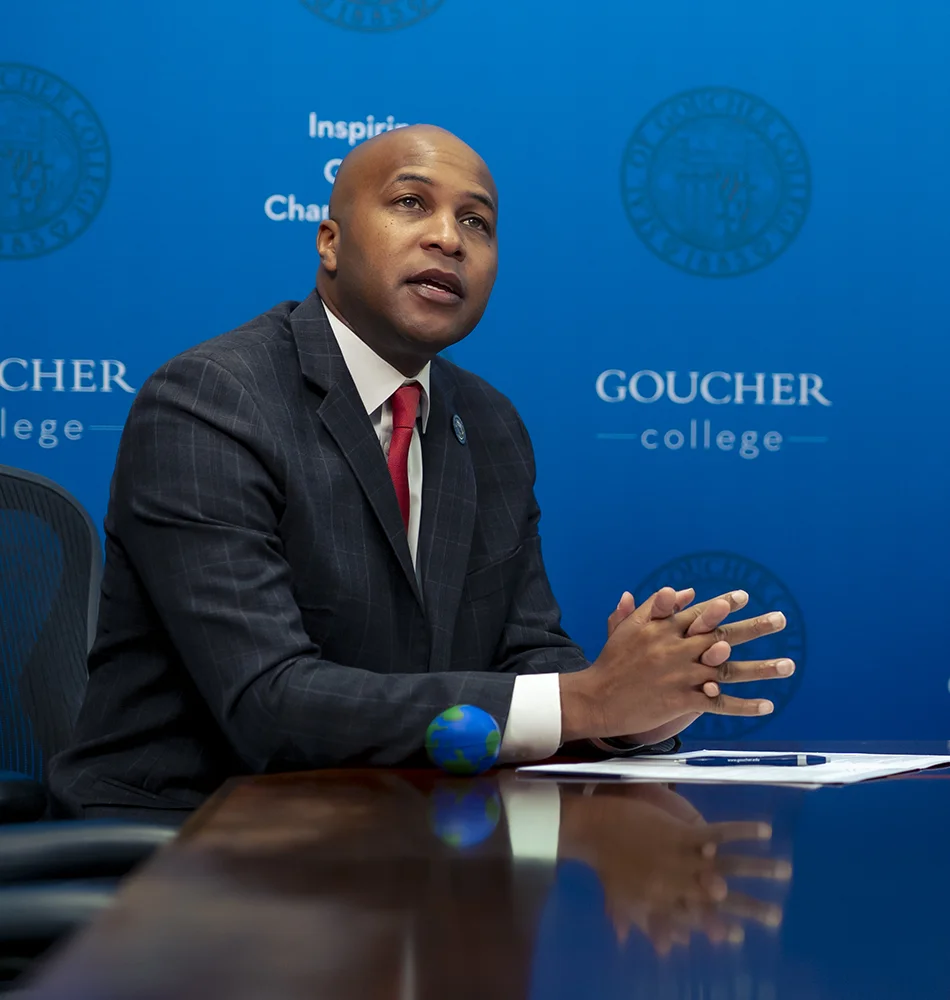 Mike Marshall speaks in front of a blue Goucher background during the Goucher College and Air University, Islamabad, partnership announcement.