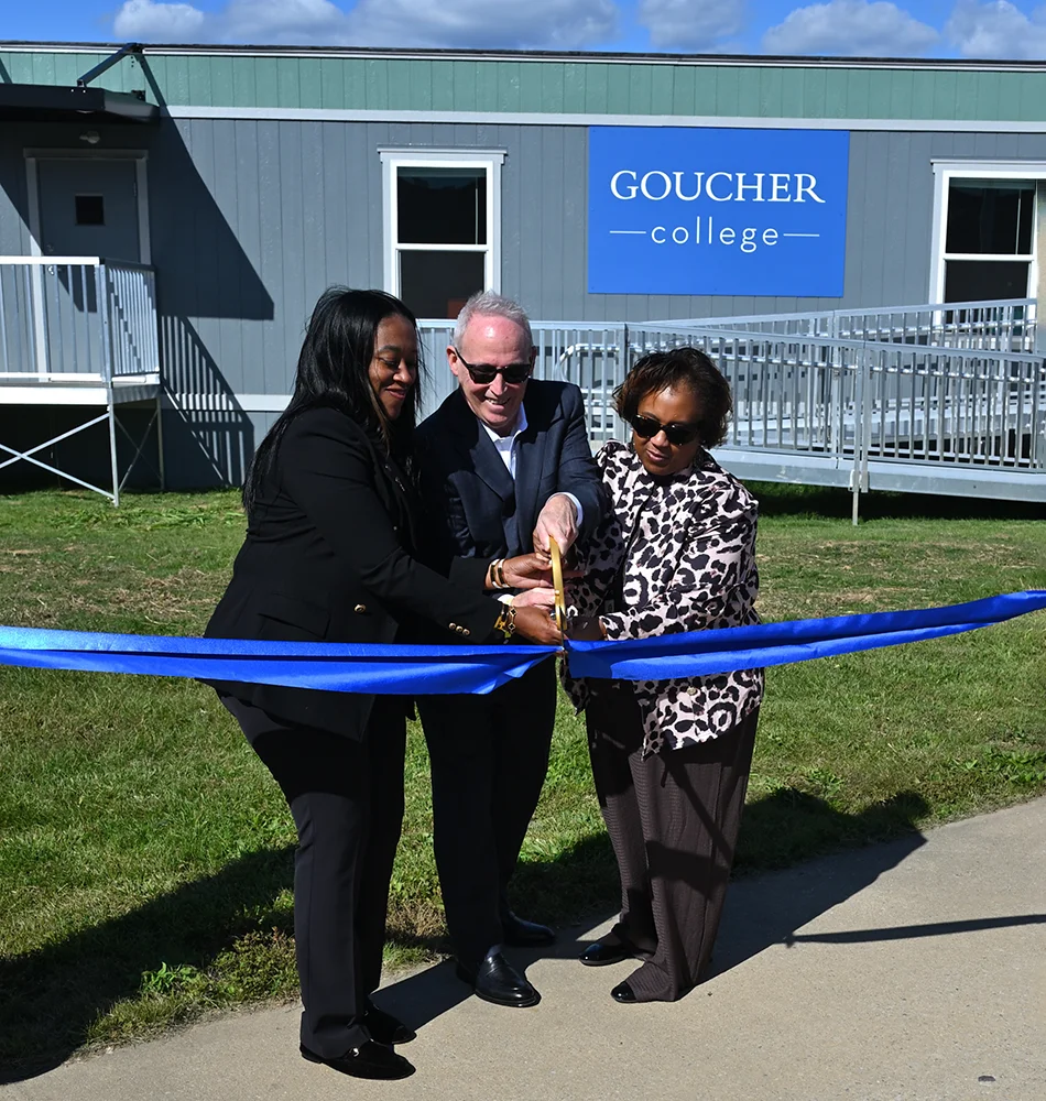 Goucher president, Kent Devereaux smiles with colleagues while cutting a bright blue ribbon in front of the state’s first prison classrooms created solely for college use at the Maryland Correctional Institution for Women in Jessup.